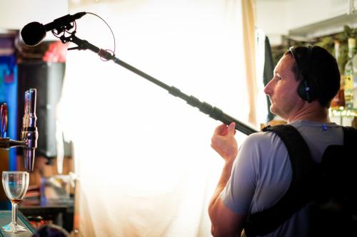 Sound recordist on a film set with ambient boom post and Sennheiser MKH50 microphone