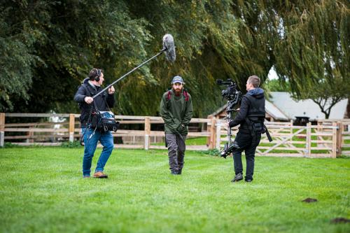 Sound recordist using rycote windshield walking with boom pole following actor with steadycam