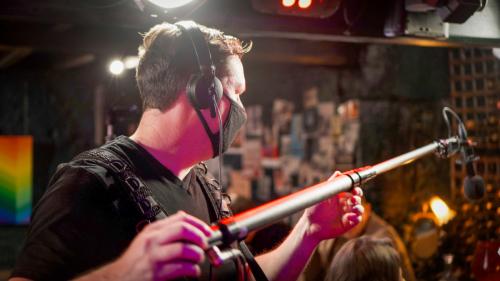 Sound recordist recording film scene in a bar